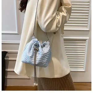 Détail du sac seau bleu clair avec texture plissée, perles et bandoulière en chaîne