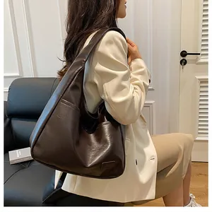 Detail of a large dark brown PU leather tote bag worn as a stylish underarm shoulder bag