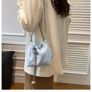 Détail du sac seau plissé bleu clair avec chaîne argentée et pendentif perle blanche