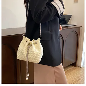 Détail d'un sac seau crème texture gaufrée avec cordon perlé et bandoulière chaîne