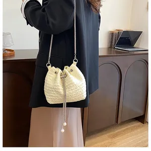 Détail du sac seau matelassé à cordon avec perles élégantes et bandoulière chaîne argent