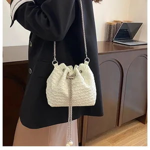 Détail du sac seau blanc plissé avec accents de perles et bandoulière en chaîne argent
