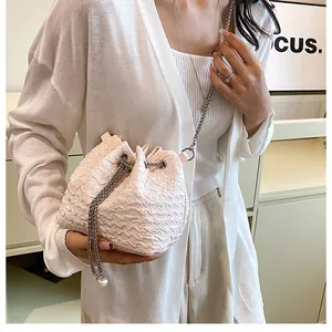 Vue détaillée du sac seau plissé rose avec chaîne argentée et perle porté par un mannequin