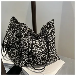 Detalle del bolso tote de lona con estampado de leopardo, correas de cuero y ojales de oro