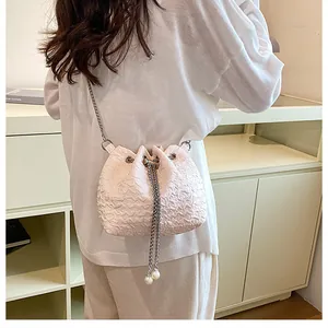 Détail du sac seau à cordon rose clair avec texture plissée et accents de perles