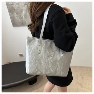 Detailed macro view of the silver pleated texture and embossed butterfly on the tote bag
