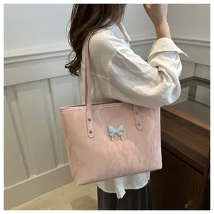 Detail of light pink pleated tote bag featuring silver butterfly charm and rivet straps