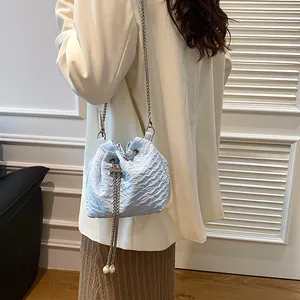 Sac seau bleu clair avec texture plissée, chaîne argentée et ornements de perles