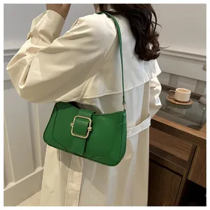 Detail of a bright green leather underarm bag featuring a bold gold square metal buckle