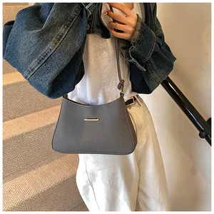Detail of grey twill shoulder bag featuring sleek gold metal hardware and slim strap