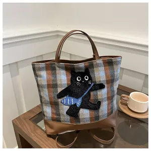 Détail du cabas à carreaux avec broderie chat mignon et garniture en cuir marron