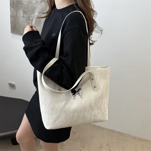 Minimalist beige tote bag with pleated texture and silver butterfly accent in side view