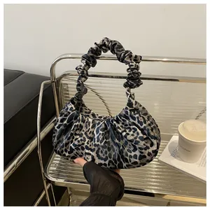 Macro detail of leopard print cloud bag with ruched handle on a metallic shelf