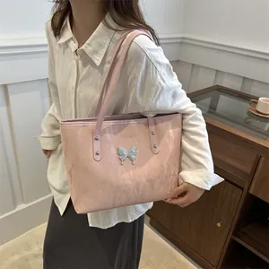 Pink faux leather tote bag with silver butterfly accent and stylish wrinkled texture