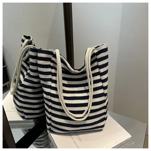 Detailed close-up of navy blue striped canvas tote bag with thick rope handles on a desk