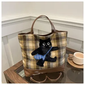 Détail du sac cabas à carreaux avec broderie chat noir et anses en cuir marron
