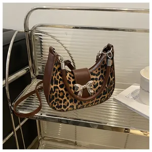 Dettaglio borsa a mezzaluna leopardata con fiocco argento e finiture in pelle marrone