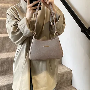 Chic beige woven underarm bag with gold bar clasp and knotted rope strap detail