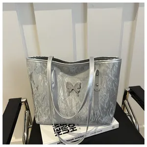 Dettaglio della borsa tote argento con texture metallica stropicciata e farfalla