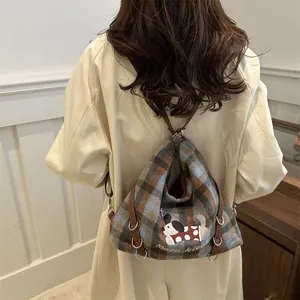 Plaid canvas tote bag with embroidered cartoon dog and leather straps worn by model
