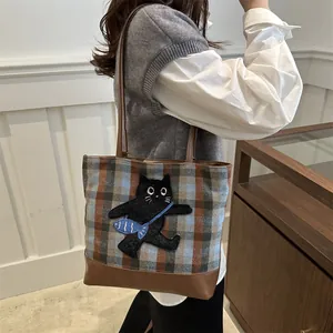 Grand sac cabas à carreaux avec broderie chat et anses en cuir porté par un mannequin
