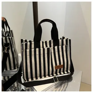 Detail view of black and white striped canvas tote with brown leather fashion label