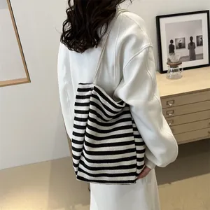 Large striped canvas tote bag with woven rope handles shown on model in a modern interior