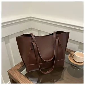 Dettaglio di una borsa tote grande in pelle marrone scuro su un tavolo di vetro
