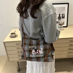 Plaid canvas tote bag with embroidered dog and brown leather strap worn over shoulder