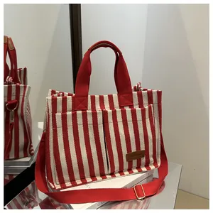 Detail of red and white striped canvas tote bag with front pockets and fashion label