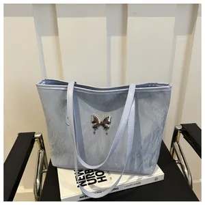 Dettaglio della borsa tote azzurra con trama a pieghe e ornamento a farfalla d'argento