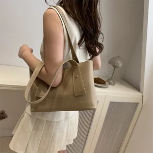 Minimalist khaki tote bag with wide shoulder strap and gold rivets for daily wear
