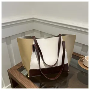Dettaglio della grande borsa tote tricolore con spalline marroni su un tavolo di legno