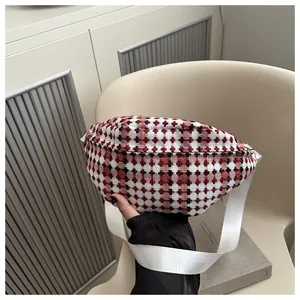 Detail van rood-wit geruite tweed heuptas met een witte geweven schouderband