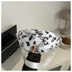 Détail d'un sac bandoulière blanc avec imprimés papillons dans un décor décontracté