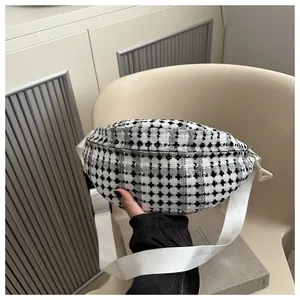 Detail van een zwart-witte tweed heuptas met een verstelbare witte schouderband voor dames