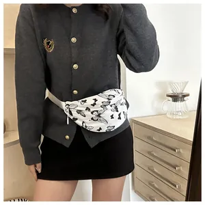 Détail du sac banane blanc à motif papillon porté avec un cardigan en maille grise