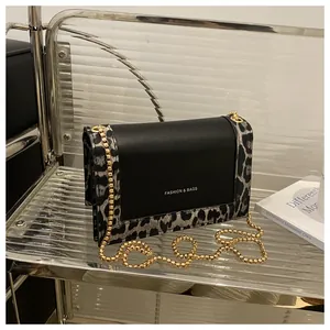 Detail of leopard print stitching and gold chain strap on black crossbody bag