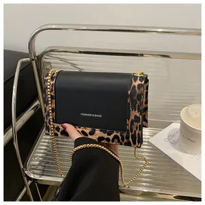 Detail of leopard print crossbody bag with black leather flap and gold chain strap