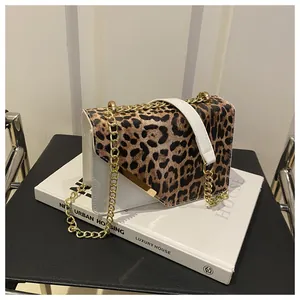 Close-up of leopard print flap and gold chain detail on a white vegan leather shoulder bag