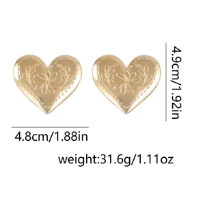 Detalle de pendientes de corazón dorados grandes con grabado floral y dimensiones