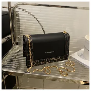 Detail of leopard print stitching and golden chain on black leather crossbody bag