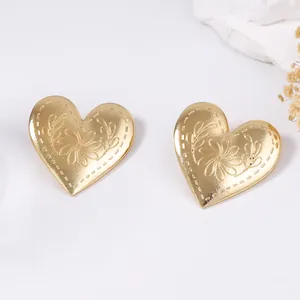 Pendientes retro de corazón dorado con motivo floral grabado sobre un fondo blanco limpio