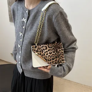Leopard print crossbody bag with gold chain strap shown on model in a modern interior