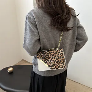 Elegant leopard print crossbody bag with gold chain strap worn over a grey sweater