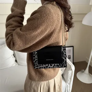 Minimalist leopard print crossbody bag with gold chain strap shown on model shoulder