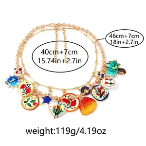 Détail du collier à double chaîne dorée avec pendentifs colorés de fleurs et de coquillages