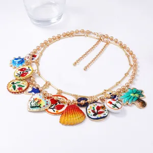 Détail d'un collier bohème à double chaîne dorée avec breloques en émail et fleurs colorées