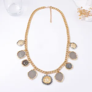 Macro view of gold chunky chain necklace with nine textured coin charms and lobster clasp