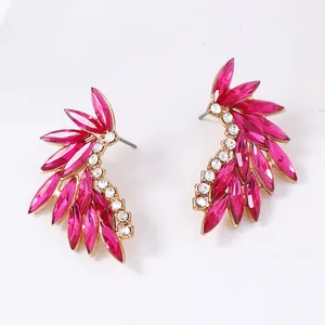 Detailed close-up of gold-plated feather stud earrings with pink marquise zircon stones